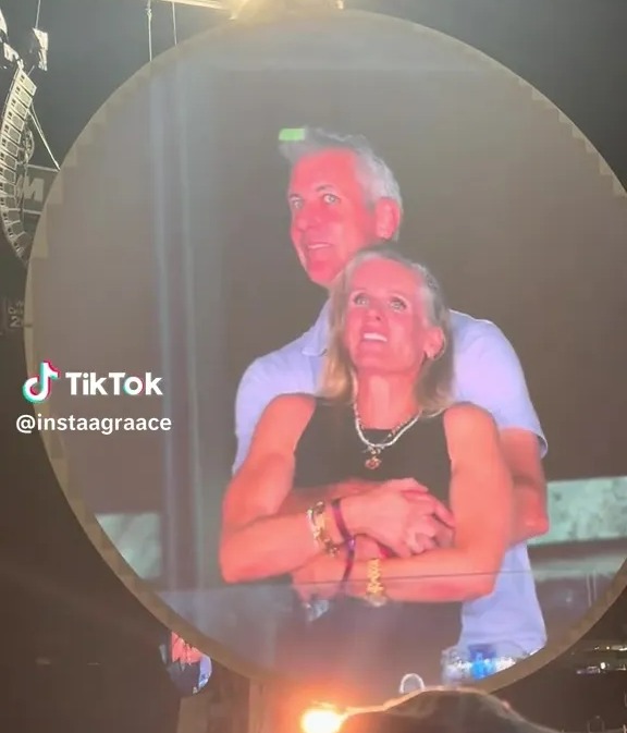 A tech CEO and his HR chief embracing on a large screen at a Coldplay concert.